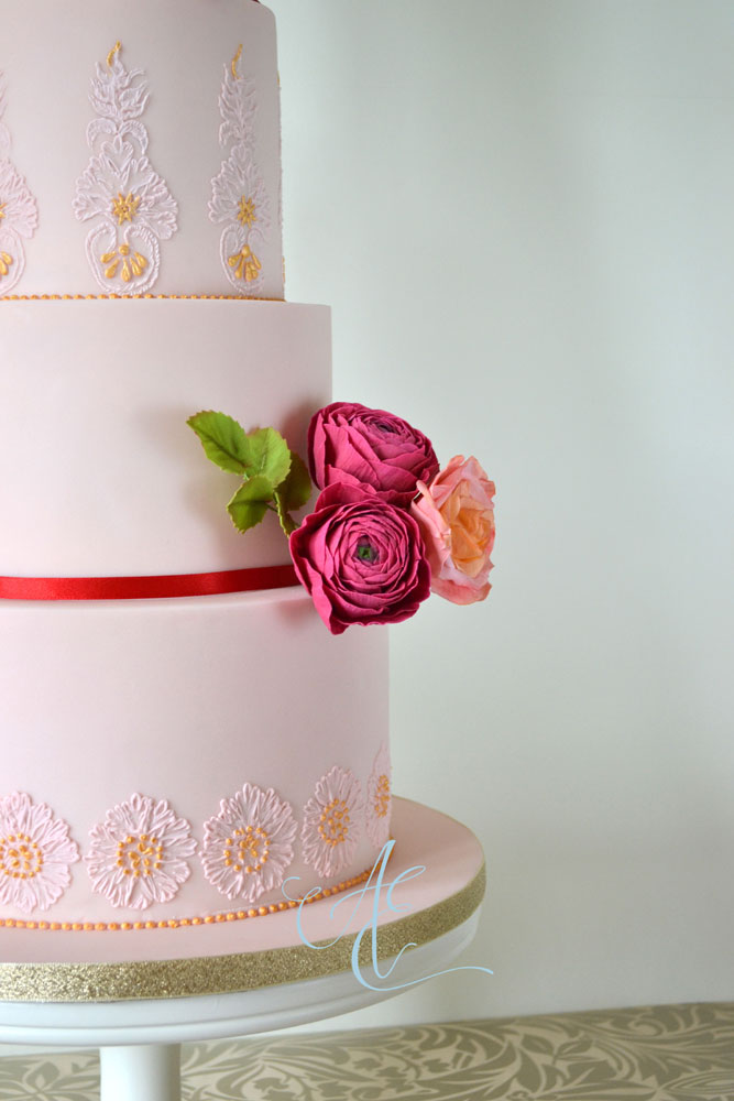 close up pink wedding cake with gilded hand piping