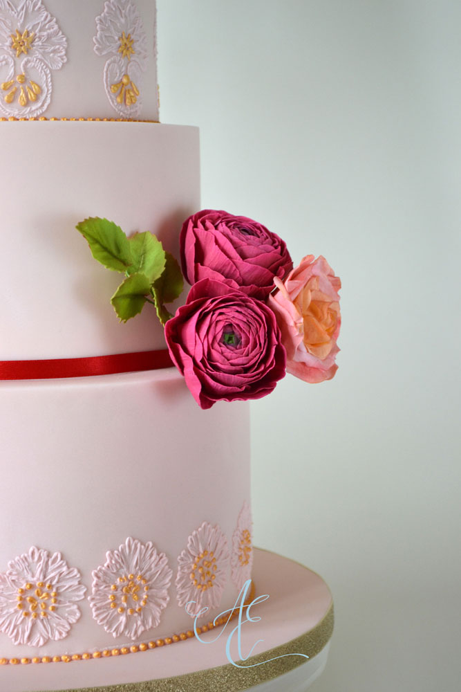 close up gilded lace piping and vibrant sugar flowers