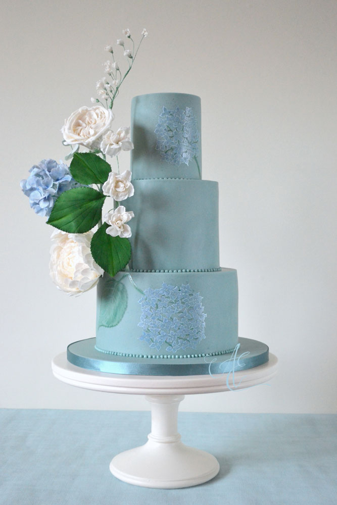 Vegan wedding cake iced in teal with blue and white vegan sugar hydrangeas and roses