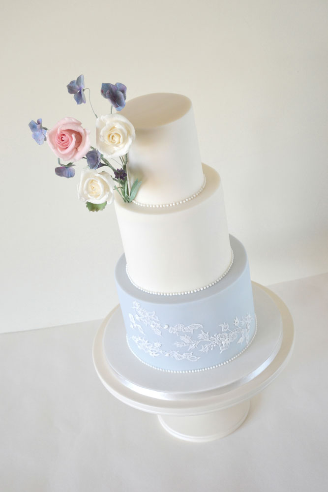 Powder blue lace wedding cake with a posy of sugar flowers
