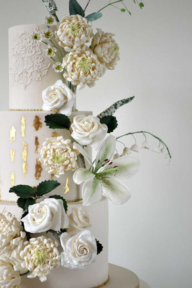 close up ivory green gold wedding cake and sugar flowers