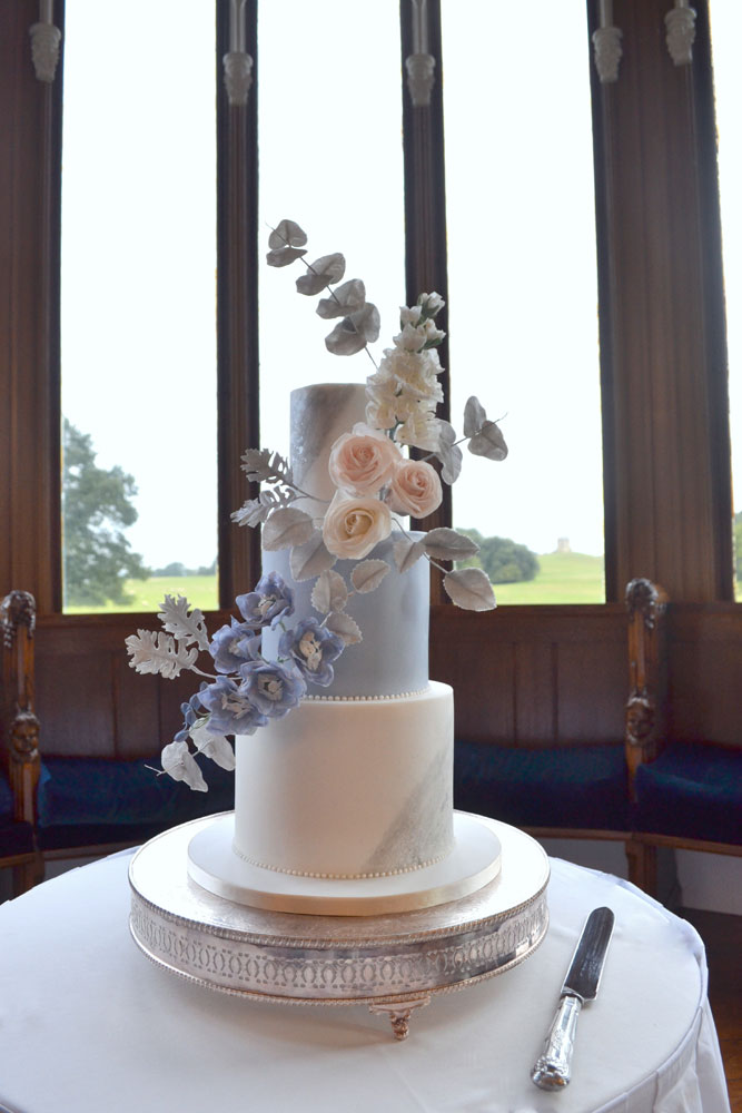 blue and white floral wedding cake on traditional silver cake stand